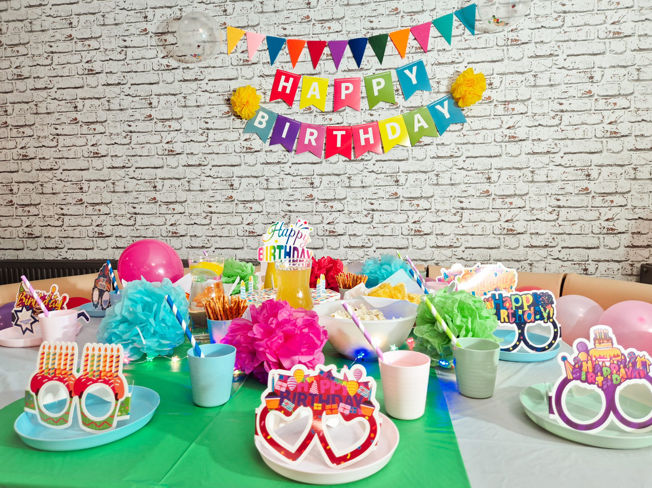 Zdjecia przerdstawia kolorowo zastawiony stół na dziecięce przyjecie urodzinowe. na scianie znajduje się napis Happy Birthsday