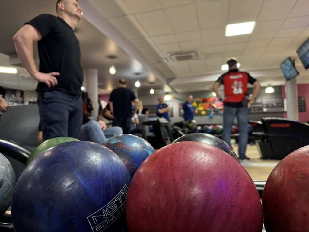 zlizenie na kule do kręgli w podajniku, w tle zawodnicy ligi bowlingowej